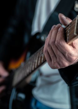 Guitarist hands and guitar strings close up. Musician man playing electric guitar. Selective focus.